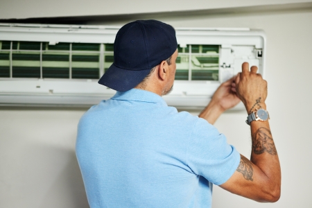 HVAC technician inspecting an air conditioner in Alliance, Ohio home
